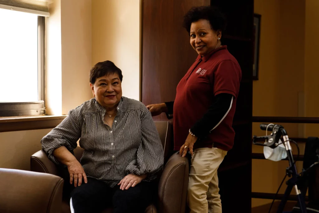 Felicia Biteranta, left, a retired nurse who has had limited mobility since she suffered a stroke, with her home health aide, Altagracia Garcia-Reyes. “She cleans and does my laundry and the shopping,” Ms. Biteranta said of Ms. Garcia-Reyes. “She knows the food I like.”Credit...Brian Fraser for The New York Times